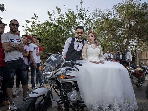 In this April 16, 2020 file photo, newlyweds are surrounded by their friends as they celebrate before a curfew imposed as a prevention measure against the coronavirus pandemic, in Cairo, Egypt. In a region where marriage is the cornerstone of society, couples are ploughing ahead with weddings, despite the deadly risks.