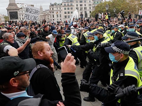 Riot police face protesters who took part in a 'We Do Not Consent' rally at Trafalgar Square, organised by Stop New Normal, to protest against coronavirus restrictions, in London, Saturday, Sept. 26, 2020.