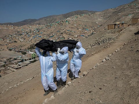Piedrangel funeral home workers Luis Zerpa, Luis Brito, centre, and Jhoan Faneite, right, from Venezuela, carry the corpse to the hearse of Marcos Espinoza, 51, who died from symptoms of coronavirus in Pachacamac, on the outskirts of Lima, Peru.