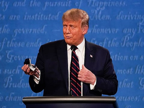President Donald Trump holds out his face mask during the first presidential debate at Case Western University and Cleveland Clinic, in Cleveland, Ohio.