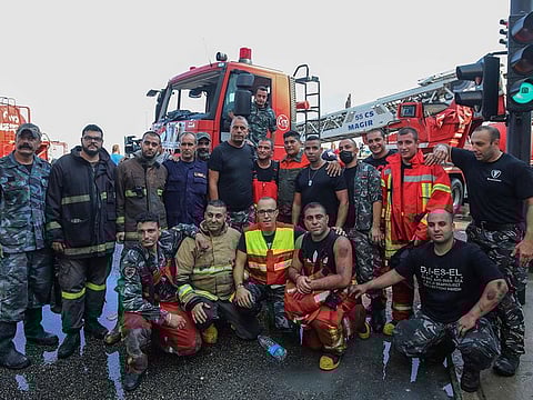 Members of the Lebanese Civil Defence and firefighting department pose for a picture after extinguishing a fire that erupted in a landmark modern building, designed by the late British-Iraqi architect Zaha Hadid, in central Beirut on September 15, 2020.