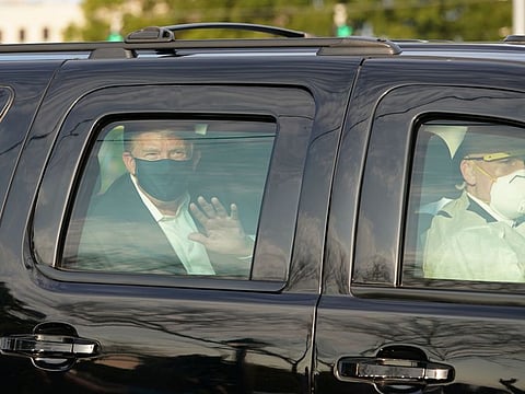 Trump waves from the back of a car in a motorcade outside of Walter Reed Medical Center in Bethesda, Maryland on October 4, 2020