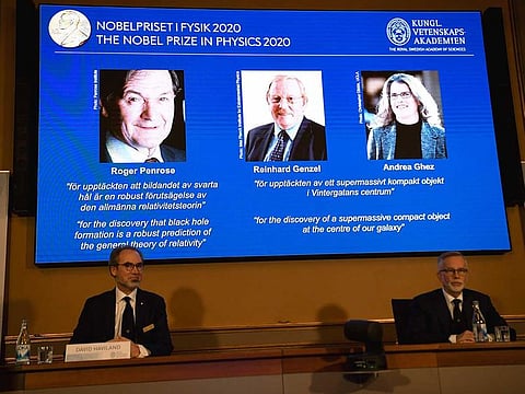 David Haviland (L), member of the Nobel Committee for Physics, and Goran K Hansson, Secretary General of the Academy of Sciences, (L-R) sit in front of a screen displaying the winners of the 2020 Nobel Prize in Physics (L-R) Briton Roger Penrose, Reinhard Genzel of Germany and Andrea Ghez of the US, during a press conference at the Royal Swedish Academy of Sciences, in Stockholm, on October 6, 2020.