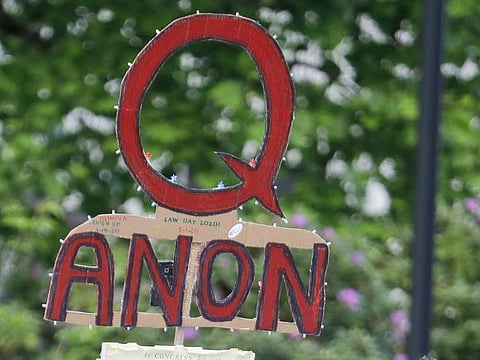 File photo: A person carries a sign supporting QAnon at a protest rally in Olympia, Washington. Facebook said Tuesday, that it will remove pages, groups and Instagram accounts for “representing QAnon.”
