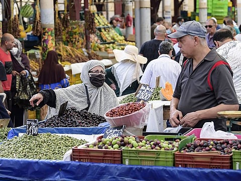 A mask-clad customer (COVID-19 coronavirus precaution) speaks with a fruit seller at his stall at the central market in Tunisia's capital Tunis on October 4, 2020. - Tunisia's Prime Minister Hichem Mechichi announced late on October 3 a set of new measures aimed at curbing the spread of the novel coronavirus in the North African country, including a ban on all gatherings and stressing the importance of wearing face masks to limit the spike in new cases.