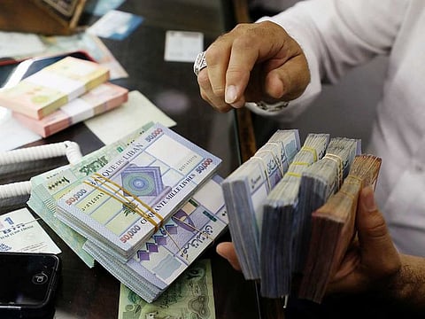 A man counts Lebanese pounds at a currency exchange shop in Beirut. The pound is currently trading at about 11,000 to the dollar on the black market, compared with the official rate pegged at 1,507.