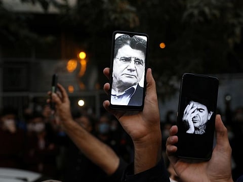 Photos of Mohammed Reza Shajarian, Iran's most celebrated musician and a critic of the government, are seen on fans' smart phones as they mourn his death in front of Jam Hospital, in Tehran on October 8, 2020.