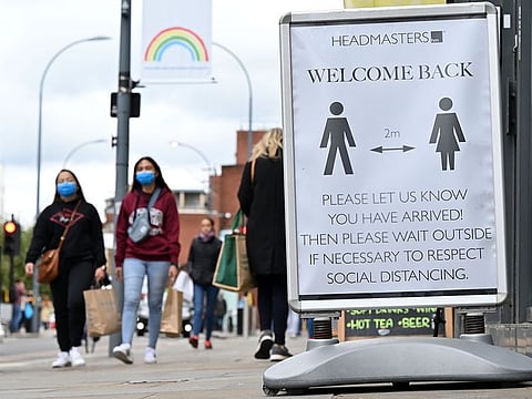 Pedestrians and shoppers, some wearing face masks as a precaution against the transmission of the novel coronavirus, walk in the high street in west London on October 11, 2020.