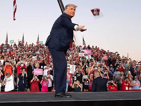 US President Donald Trump throws masks to supporters as he arrives to hold a Make America Great Again rally as he campaigns at Orlando Sanford International Airport in Sanford, Florida, October 12, 2020.