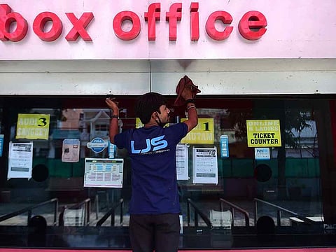 A worker cleans the ticket counter outside a theatre hall on the eve of the scheduled reopening of cinema theatres as the Covid-19 coronavirus imposed lockdown eases further in Allahabad on October 14, 2020.