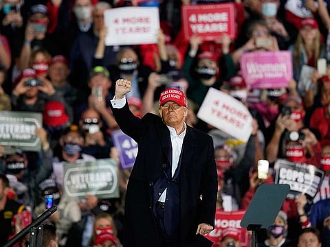 President Donald Trump pumps his fist at supporters after speaking at an airport campaign rally, Wednesday, Oct. 14, 2020, in Des Moines, Iowa.