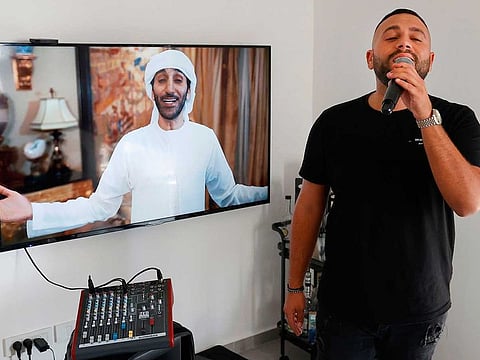 Israeli singer Elkana Marziano, 28, sings along with a video clip of a song on which he worked in collaboration with Emirati artist Walid Aljasim (image on screen), during an interview with AFP at his home in the central Israeli city of Giv'at Shmuel.