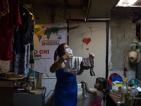 Norelys, 40, hangs her laundry to dry at a shelter located in the basement of the Sudameris public building, next to her daughter, in Caracas, on October 9, 2020, amid the new coronavirus pandemic.