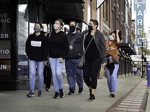 Pedestrians wearing protective mask pass in front of the Fargo Theatre in downtown Fargo, North Dakota, U.S., on Wednesday, Oct. 14, 2020. The North Dakota Department of Health on Thursday, Oct. 15, reported five deaths from COVID-19 and another record-high number of active cases.