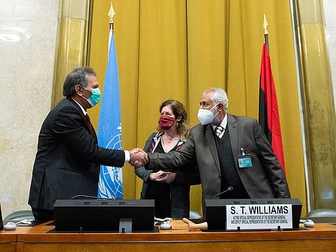 This handout photo released on October 23, 2020 by the United Nations Office in Geneva shows Head of the Libyan Arab Armed Forces delegation A. Amhimmid Mohammed Alamami (left) and Head of the Government of National Accord’s (GNA) military delegation Ahmed Ali Abushahma shaking hands next to deputy special representative of the UN Secretary-General for Political Affairs in Libya Stephanie Williams on October 23, 2020 in Geneva.