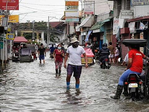 Residents wearing masks to prevent the spread of the coronavirus wade through a flooded road from Typhoon Molave in Pampanga province, northern Philippines on Monday, Oct. 26, 2020. The fast moving typhoon has forced thousands of villagers to flee to safety in provinces.