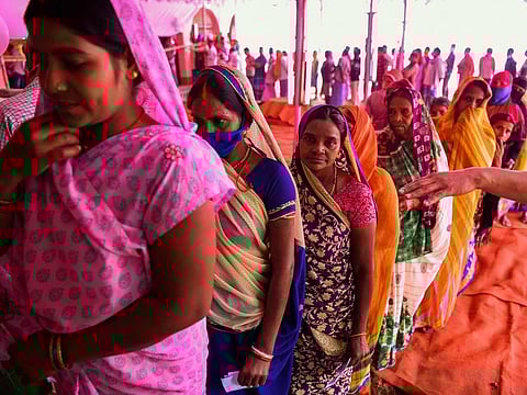 Voters queue up to cast their ballots for Bihar state assembly elections at a polling station in Masaurhi on October 28, 2020