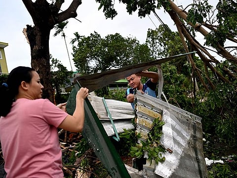 A couple clears debris outside their house next to uprooted trees in central Vietnam's Quang Ngai province on October 28, 2020, in the aftermath of Typhoon Molave.