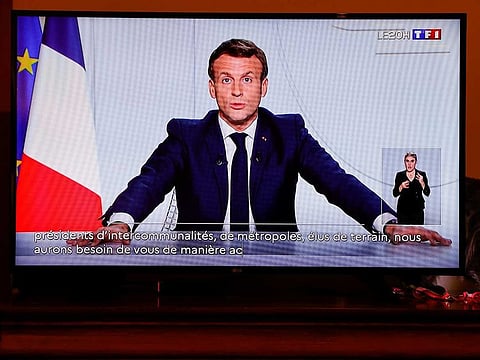 French President Emmanuel Macron is seen on a screen as he addresses the nation about the state of the coronavirus outbreak in Blecourt, France.