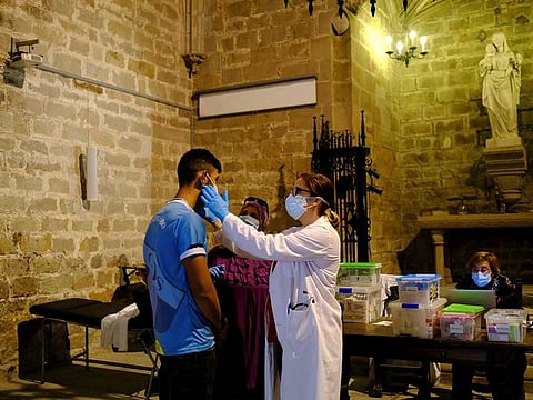 A man receives medical treatment by Merce Lopez, 42, who is a a volunteer doctor doing health checks for people amid economic hardship inside Parish Church of Santa Anna, after Catalonia's government imposed new restrictions in an effort to control the spread of the coronavirus disease (COVID-19), in Barcelona, Spain October 29, 2020.