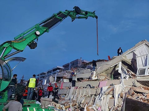 People search for survivors at a collapsed building after a strong earthquake struck the Aegean Sea where some buildings collapsed in the coastal province of Izmir, Turkey.