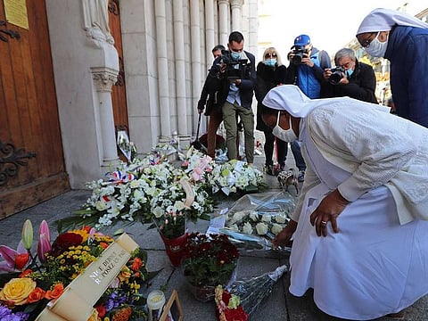 Two nuns lay flowers in front of the Notre-Dame de l'Assomption Basilica in Nice on October 30, 2020 during a tribute to the victims killed by a knife attacker the day before.