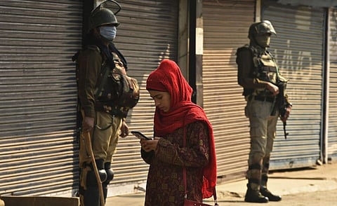 A resident walks past Indian army soldiers standing guard next to closed shops during a one-day strike called by the All Parties Hurriyat Conference (APHC) against the Indian government decision to open Kashmir land for all Indians, in Srinagar on October 31, 2020.
