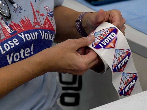 A poll worker unrolls Las Vegas Strip-themed "I Voted" stickers for voters at a polling place at the Veterans Memorial Leisure Center on November 3, 2020 in Las Vegas, Nevada.