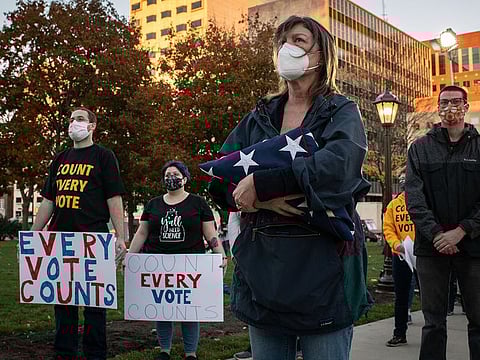 People wearing masks to stop the spread of coronavirus gather to support counting votes while ballots in the presidential election are still being counted in Lansing, Michigan, November 4, 2020.