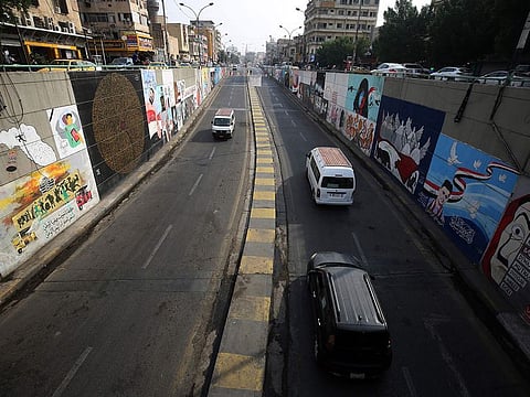 Cars drive out of a tunnel in front of walls covered with murals painted by an anti-government protesters near Tahrir Square in the centre of Iraq's capital Baghdad on November 8, 2020.