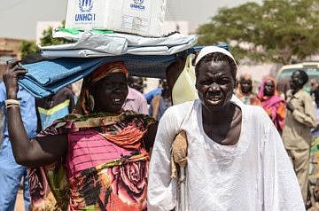 Flood-affected South Sudanese refugees gather for a UNHCR distribution of plastic sheeting, mats, blankets, mosquito nets and kitchen sets, in Sharq Al-Nile, Sudan.