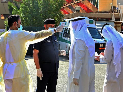A health official checks the body temperature of candidates for the upcoming Kuwaiti parliamentary election as they arrive at the Department of Elections in Kuwait City on the first day of candidate registration, on October 26, 2020.