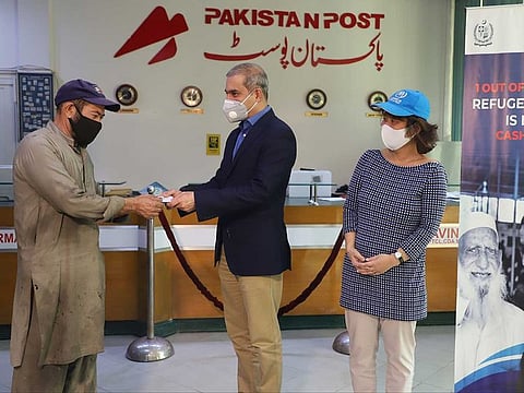 UNHCR Regional Director for Asia and the Pacific, Indrika Ratwatte, hands over emergency cash assistance to an Afghan refugee at Pakistan Post Office in Islamabad. UNHCR
