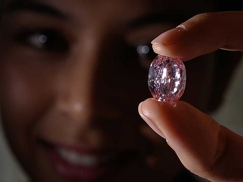 In this file photo taken on November 06, 2020, a model poses with the “The Spirit of the Rose” a rare 14,83 carats vivid purple pink diamond, during a press preview ahead of sales by Sotheby's auction house, in Geneva. The rare pink diamond derived from the biggest raw stone of the colour ever found in Russia was sold for 26,6 million USD on November 11, 2020, at Sotheby's in Geneva. AFP