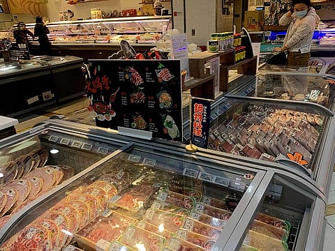 A woman wearing a face mask following the coronavirus disease (COVID-19) outbreak checks imported frozen meat at a supermarket in Beijing, China November 17, 2020.