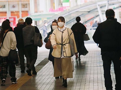 People wearing face masks to help curb the spread of the coronavirus walk at an underpass in Tokyo, Wednesday, Nov. 18, 2020.
