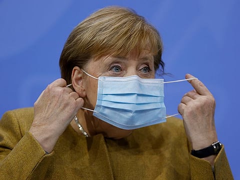 German Chancellor Angela Merkel takes off her face mask as she arrives for a press conference following talks via video conference with Germany's state governors on extending coronavirus restrictions at the Chancellery in Berlin, Wednesday, Nov. 25, 2020.