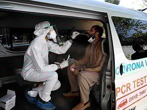 A health official collects a swab sample from a man to test for the COVID-19 coronavirus inside a van along the roadside in Islamabad. According to the National Command & Operation Centre (NCOC) after 59,745 tests conducted in past 24 hours, the COVID-19 positivity rate also dropped from 6.65 per cent to 6.33 per cent.