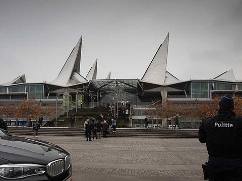 People wait in a line as police patrol outside the courthouse in Antwerp, Belgium, Friday, Nov. 27, 2020.