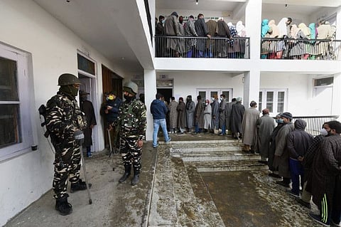 People wait to cast their votes at a polling booth during the first phase of the District Development Council (DDC) elections, in Hariganiwan area of Gund in Ganderbal district of central Kashmir, Saturday.