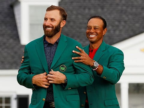 Dustin Johnson is presented with the green jacket by Tiger Woods after winning The Masters at the Augusta National Golf Club in Augusta, Georgia.