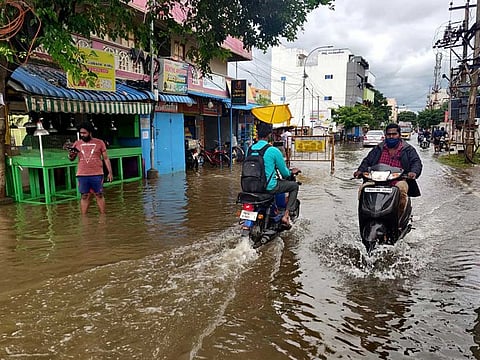 People cross a waterlogged street after heavy rainfall due to Cyclone Nivar in Chennai on Friday, November 27, 2020.