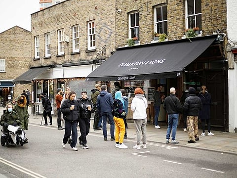 People queue up and wait for their takeaway orders outside the Climpson & Sons specialty coffee cafe, which is only allowed to open for takeaway orders during England's second coronavirus lockdown, on Broadway Market in Hackney, east London, Tuesday, Nov. 17, 2020.