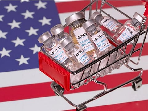 A small shopping basket filled with vials labeled "COVID-19 - Coronavirus Vaccine" is placed on a U.S. flag in this illustration taken November 29, 2020. Picture taken November 29, 2020.