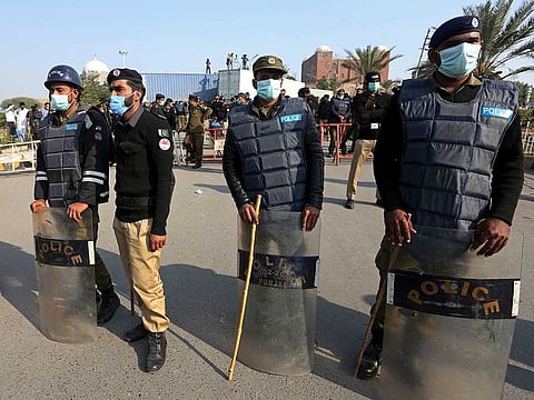 Pakistani police officers stand guard next to shipping containers blocking the path to a public park where the supporters of Pakistan Democratic Movement, an alliance of opposition parties, held a rally in Multan, Pakistan, Monday, Nov. 30, 2020.