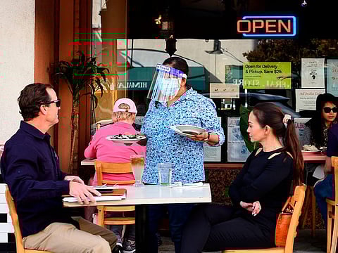 A waitress serves guests as people dine outdoors in Pasadena, California, the only city in Los Angeles County still allowing that service on December 2, 2020.