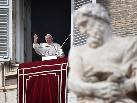 In this photo taken on November 29, 2020 Pope Francis waves to worshippers from the window of the apostolic palace overlooking St. Peter's Square during the weekly Angelus prayer in the Vatican.