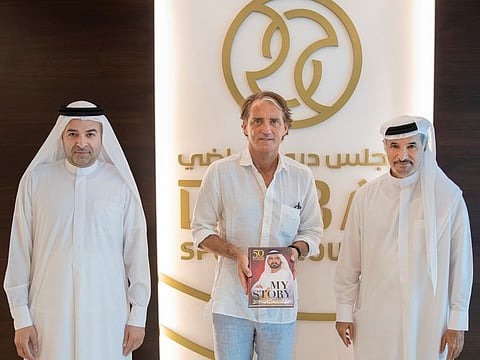 Italy manager Roberto Mancini (centre) poses with a copy of 'My Story,' authored by Sheikh Mohammad, and presented to him by the Dubai Sports Council authorities.