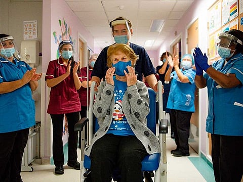 Margaret Keenan (C), 90, is applauded by staff as she returns to her ward after becoming the first person to receive the Pfizer-BioNtech COVID-19 vaccine at University Hospital in Coventry, central England, on December 8, 2020.
