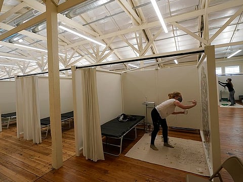 Artists Livia Westcott-Lahar, foreground, and Lauren Szabo paint walls next to beds set up at an Alternative Care Site for the City and County of San Francisco, a low acuity continuing care field hospital not yet open to patients, in San Francisco, Monday, Dec. 7, 2020.